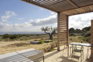 a patio with a table and chairs and a view of the desert at Cala Rossa Lodge in Favignana