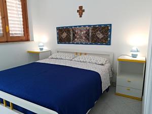 サン・ヴィート・ロ・カーポにあるSAN VITO LO CAPO APPARTAMENTO A 2 PASSI DALLA SPIAGGIAのベッドルーム1室(青いベッド1台、壁にクロス付)