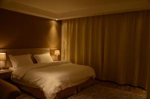 1 dormitorio con 1 cama grande con sábanas blancas en منازل الشمال للشقق المخدومة Manazel Al Shamal Serviced Apartments en Hail