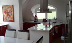uma cozinha com armários vermelhos e um balcão branco em Apartment Sagittarius em Kyustendil