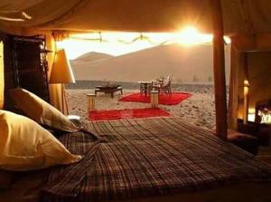 a bedroom with a bed in front of a beach at Maroc Sahara Luxury Camp & Tours in Foum Zguid