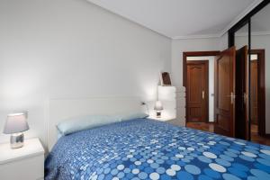 Un dormitorio con una cama azul y blanca en una habitación en Arena en Perlora, en Gijón
