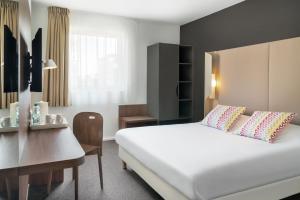 a bedroom with a large white bed and a desk at Campanile Katowice in Katowice