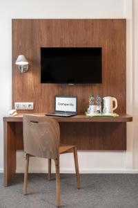 a desk with a laptop and a television on it at Campanile Katowice in Katowice