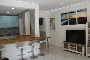 a kitchen with a bar and a tv in a room at Casas & Papeis T-4 in Armação de Pêra