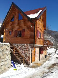 uma cabana de madeira na neve com um nevão em Vila Jelena em Crni Vrh