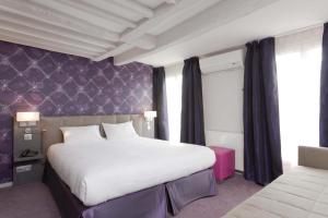 a bedroom with a large bed and a purple wall at Hotel Massena in Paris