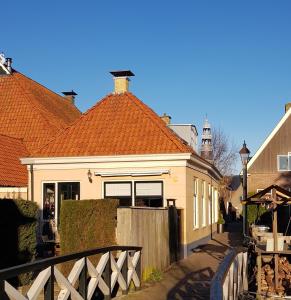 une maison avec un toit orange et une clôture dans l'établissement Atelier B&B 'Sinnestriel', à Hindeloopen