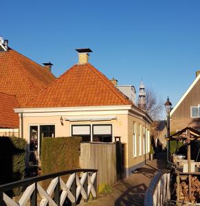 een huis met een oranje dak en een hek bij Atelier B&B 'Sinnestriel' in Hindeloopen