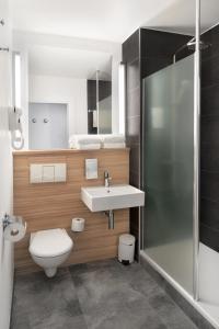 a bathroom with a sink and a toilet and a shower at Campanile Katowice in Katowice