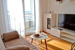 ein Wohnzimmer mit einem Sofa, einem TV und einem Tisch in der Unterkunft Apartman MiMe in Stanići