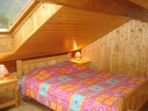 1 dormitorio con 1 cama en una habitación de madera en La Biolette, en Faverges