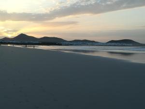 a beach with mountains in the background and the ocean at El Charquito in Famara