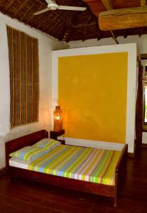 ein Schlafzimmer mit einem Bett und einer gelben Wand in der Unterkunft Patio dos quintalinhos - Casa di Gabriele in Ilha de Moçambique