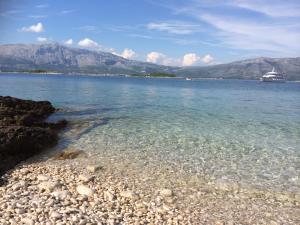 a rocky beach with a cruise ship in the water at ECO Aparthotel The Dreamers's Club in Lumbarda