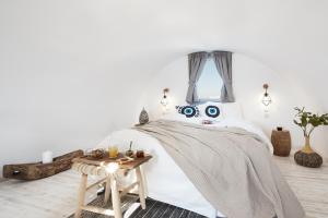 a bedroom with a bed with a blanket and a table at Pnoi Luxury Suites in Karterados