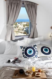 a bed with white pillows and a window with a view at Pnoi Luxury Suites in Karterados