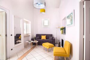 a living room with a blue couch and yellow chairs at Maison M. - Luxury Apartment in Piazza Tasso in Sorrento