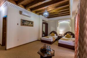 a hotel room with two beds and a table at Kukaldosh Boutique Hotel in Bukhara