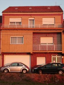 two cars parked in front of a brick building at As Carreiras in Bueu