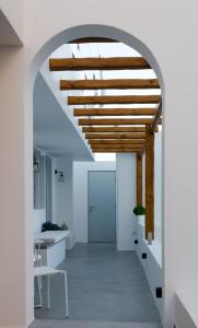une arche menant à un couloir avec des murs blancs et des plafonds en bois dans l'établissement L’arco Milos Suite, à Adamas