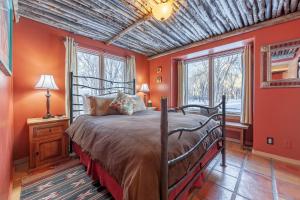 um quarto com paredes cor de laranja, uma cama e janelas em Adobe and Pines Inn Bed and Breakfast em Taos