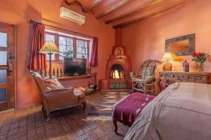 1 dormitorio con chimenea, 1 cama y TV en Adobe and Pines Inn Bed and Breakfast en Taos