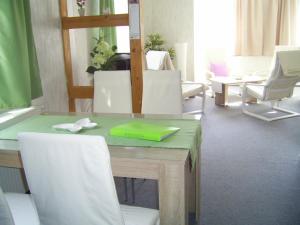 uma mesa com cadeiras brancas e uma tábua de cortar verde em Ferien-/ Monteurwohnung Nette em Themar