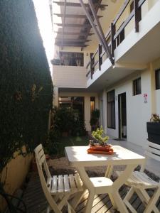 eine Terrasse mit einem weißen Tisch und Stühlen vor einem Gebäude in der Unterkunft Cabinas Gosen in Puntarenas