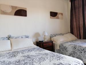 1 dormitorio con 2 camas y mesa con lámpara en Cabinas Gosen en Puntarenas
