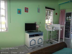 Droomstudio seru coral 32 في فيليمستاد: غرفة معيشة مع تلفزيون بشاشة مسطحة على جدار