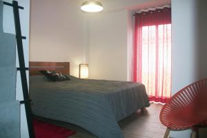 um quarto com uma cama, uma cadeira e uma janela em Friendly Peniche Apartment em Peniche