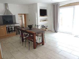 a kitchen with a wooden table and chairs and a television at La Maison d’Elise in Beine