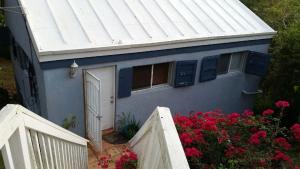 ein blaues Haus mit einer weißen Tür und einem Zaun in der Unterkunft The Cottage at Villa Indigo in Charlotte Amalie