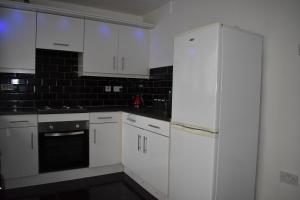 a white kitchen with white cabinets and black appliances at Redwood House in Liverpool