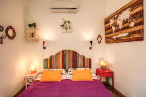 1 dormitorio con 1 cama morada y 2 almohadas de color naranja en Urban Chic Studio - by BRAVE, en Roma
