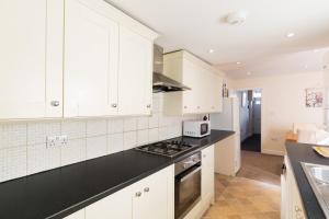 a kitchen with white cabinets and a black counter top at Leamington Spa Town House 2-Bed, 2 Bath in Leamington Spa