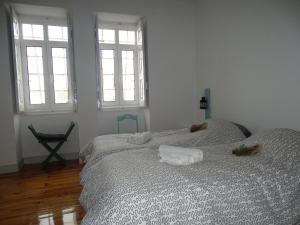 a white bedroom with a bed with two windows at Penhas da Saúde in Penhas da Saúde