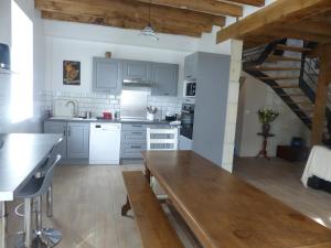 une cuisine avec des placards blancs et une table en bois dans l'établissement La maison de Joëlle, à Châteauvieux