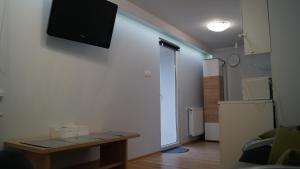 a room with a table and a television on a wall at Apartament Bajka in Rumia
