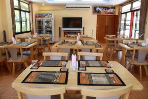 un restaurante con mesas y sillas de madera y TV en Ben Guesthouse, en Chiang Rai