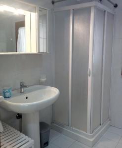 a white bathroom with a sink and a shower at Ancilinas House in Castellammare del Golfo