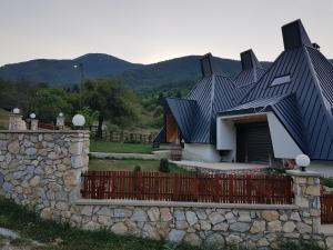 a house with a black roof with a stone wall at Vila Piramida in Bitola