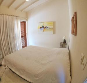 Habitación blanca con cama y ventana en Casa Ilhabela Lado Sul - Próx. Praia do Curral, en Ilhabela