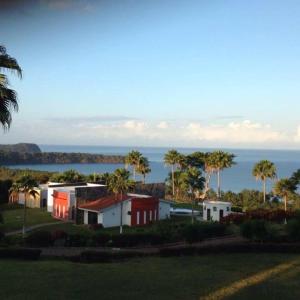 un groupe de maisons, de palmiers et de l'océan dans l'établissement Playa Limoncito Hills Fraccionamiento Vacacional Villas de 2 & 3 Recamaras con Alberca Privada o Alberca Compartida, à Limoncito Hill