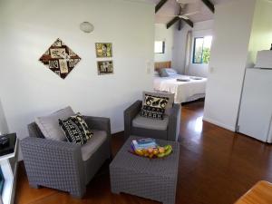 a living room with two chairs and a bed at Aroa Kainga Bungalows and Apartment in Rarotonga