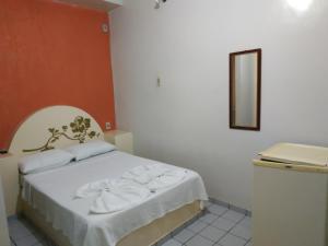 a bedroom with a white bed with a mirror at Pousada NP in Conceição da Barra