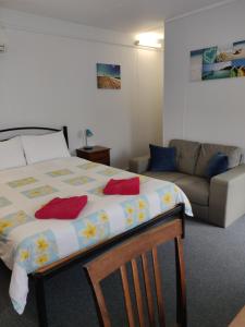 a bedroom with a bed, chair, and table at Summers Rest Units in Port Campbell
