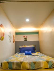a bedroom with a bed with a yellow and blue comforter at Napsule Suites in Davao City