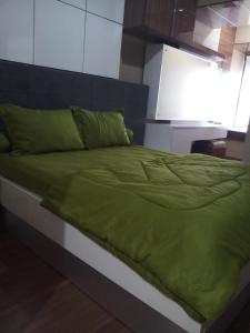 a bed with a green comforter in a room at The Sixth Room in Yogyakarta +7 photos